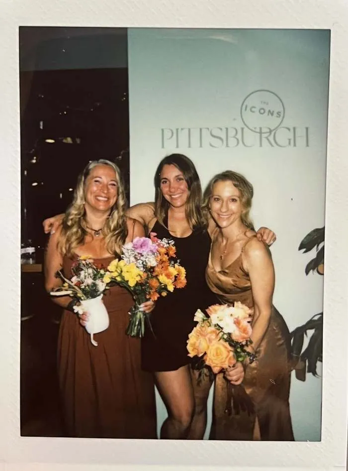 Three ICONS members holding flower bouquets at an ICONS of Pittsburgh event